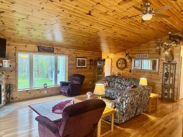 870 Dalton Dr, Rose City, MI 48654 - living room with wooden walls, lofted ceiling, wood finished floors, ceiling fan, and a stone fireplace