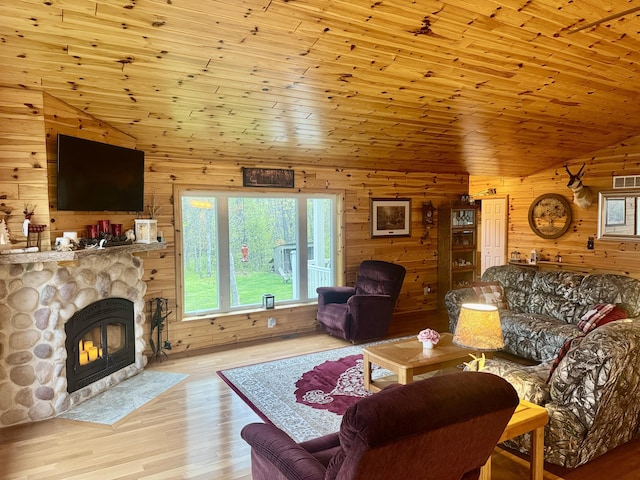 870 Dalton Dr, Rose City, MI 48654 - living room featuring wood walls, wood finished floors, a stone fireplace, and vaulted ceiling