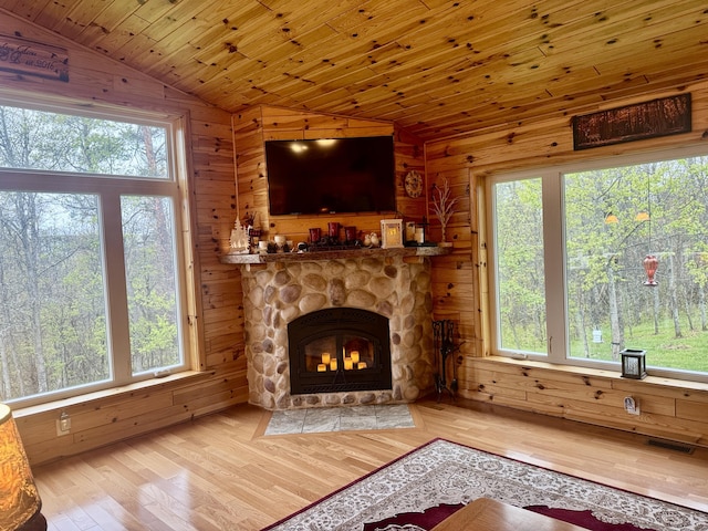 870 Dalton Dr, Rose City, MI 48654 - unfurnished living room featuring lofted ceiling, wooden walls, wood finished floors, plenty of natural light, and a fireplace