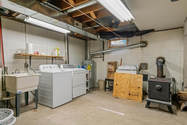 6727 Fisher Woods Rd, Indian River, MI 49749 - unfinished below grade area with independent washer and dryer, water heater, a sink, a wood stove, and concrete block wall