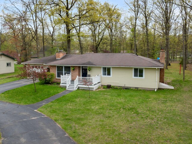 6727 Fisher Woods Rd, Indian River, MI 49749 - ranch-style house with a chimney, a porch, a front yard, driveway, and brick siding