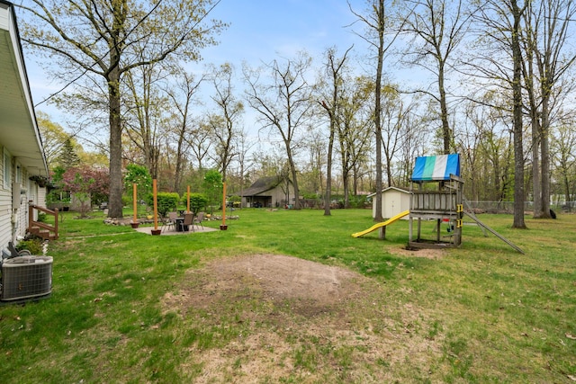 6727 Fisher Woods Rd, Indian River, MI 49749 - view of green lawn featuring a playground, central air condition unit, and an outbuilding