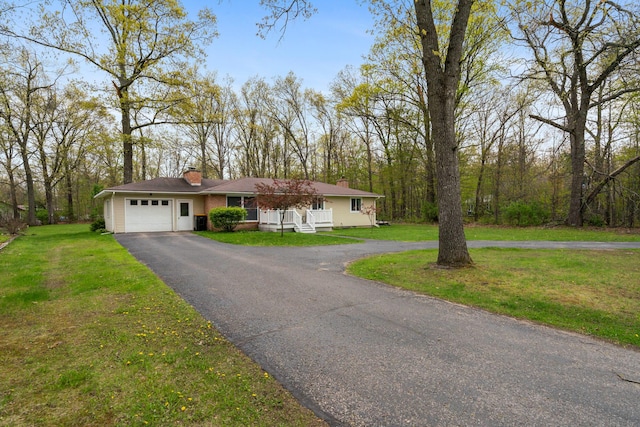 6727 Fisher Woods Rd, Indian River, MI 49749 - view of front of home featuring a chimney, driveway, a garage, a front yard, and covered porch