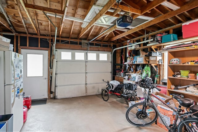 6727 Fisher Woods Rd, Indian River, MI 49749 - garage featuring a garage door opener and freestanding refrigerator