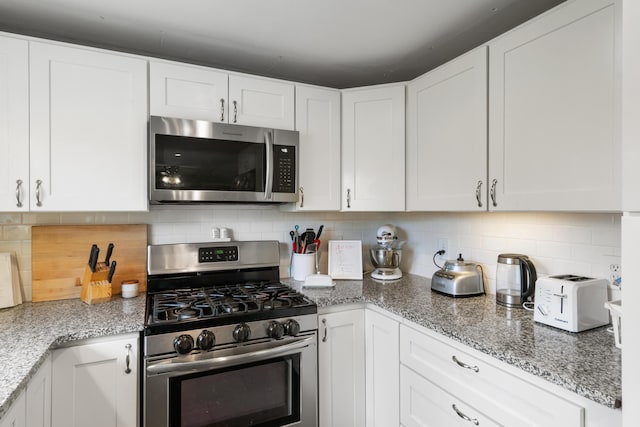 6727 Fisher Woods Rd, Indian River, MI 49749 - kitchen featuring appliances with stainless steel finishes, white cabinetry, decorative backsplash, and light stone counters