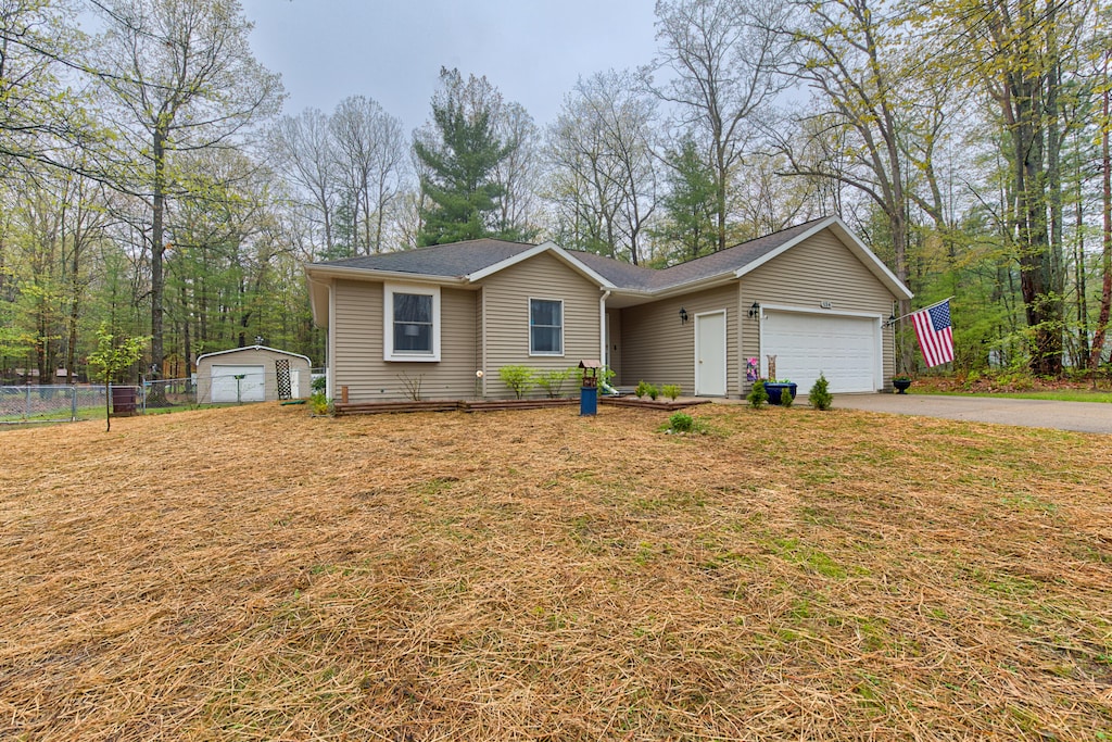 134 Teaberry Ln, Houghton Lake, MI 48629 - view of front facade featuring asphalt driveway, fence, a garage, and roof with shingles