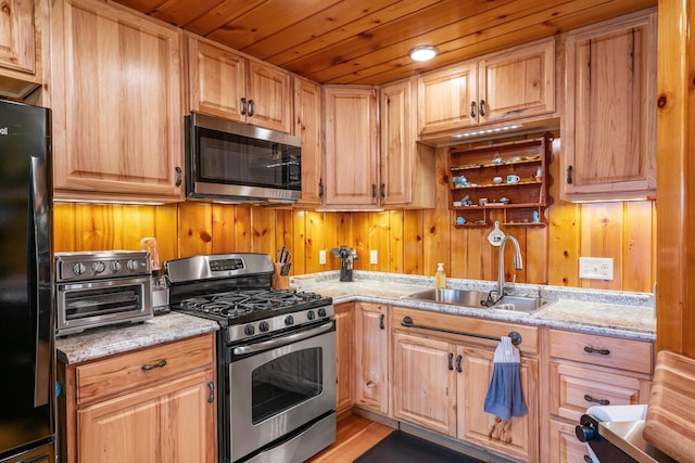 2286 Maxwell Rd, Petoskey, MI 49770 - kitchen featuring appliances with stainless steel finishes, a sink, wood walls, light stone counters, and wooden ceiling