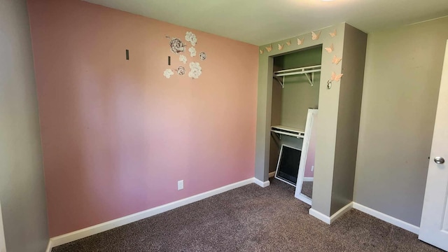 6131 N F41, Spruce, MI 48762 - unfurnished bedroom with a closet, dark carpet, and baseboards