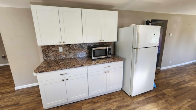 6131 N F41, Spruce, MI 48762 - kitchen featuring freestanding refrigerator, stainless steel microwave, baseboards, decorative backsplash, and white cabinetry
