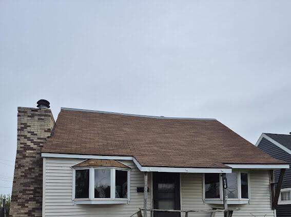 view of front of house with roof with shingles and a chimney