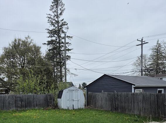 view of yard featuring fence, a shed, and an outbuilding