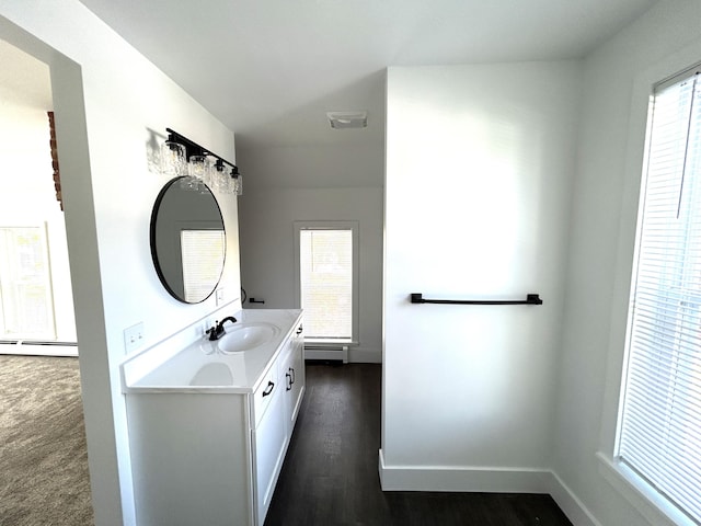 1033 S First Ave, Alpena, MI 49707 - bathroom featuring a baseboard radiator, vanity, wood finished floors, and baseboards
