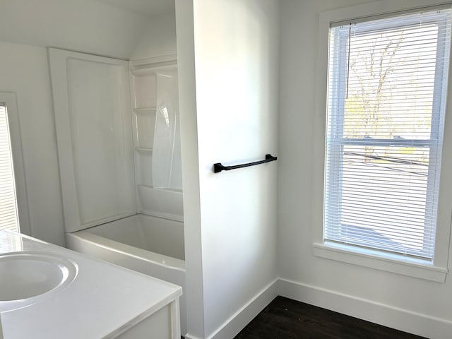 1033 S First Ave, Alpena, MI 49707 - bathroom featuring baseboards, wood finished floors, vanity, and bathtub / shower combination