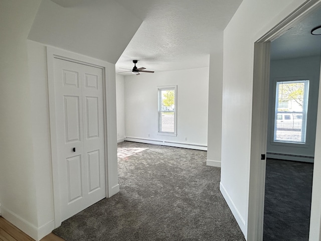 1033 S First Ave, Alpena, MI 49707 - carpeted empty room with a baseboard heating unit, ceiling fan, baseboards, and a textured ceiling