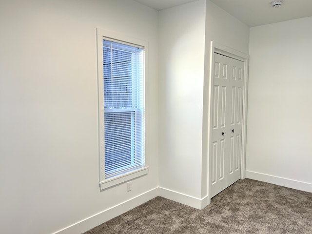 1033 S First Ave, Alpena, MI 49707 - unfurnished bedroom featuring dark carpet, baseboards, and a closet
