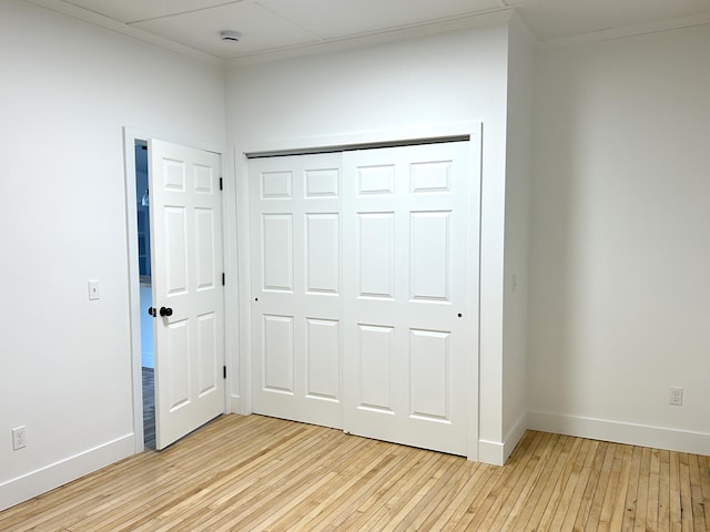 1033 S First Ave, Alpena, MI 49707 - unfurnished bedroom featuring ornamental molding, light wood-style floors, baseboards, and a closet