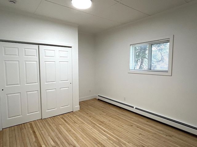 1033 S First Ave, Alpena, MI 49707 - unfurnished bedroom featuring baseboard heating, light wood finished floors, and a closet