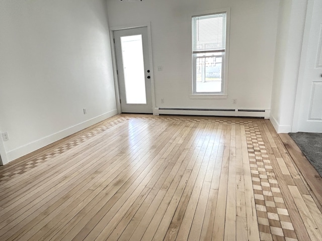 1033 S First Ave, Alpena, MI 49707 - unfurnished room with a baseboard radiator, light wood-style floors, and baseboards