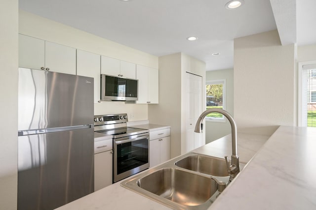 2067 Woods Ln, Petoskey, MI 49770 - kitchen featuring appliances with stainless steel finishes, a sink, light countertops, white cabinets, and recessed lighting