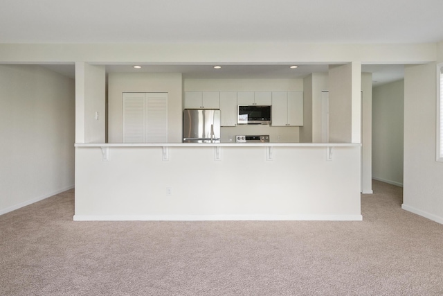 2067 Woods Ln, Petoskey, MI 49770 - kitchen with stainless steel appliances, light colored carpet, a kitchen bar, and recessed lighting