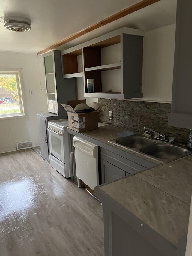 420 W Miller St, Alpena, MI 49707 - kitchen with white dishwasher, tasteful backsplash, a sink, light wood-style floors, and open shelves