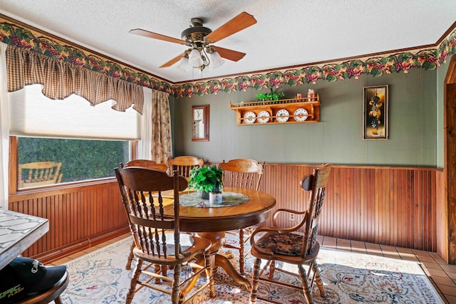 6620 N Straits Hwy, Cheboygan, MI 49721 - dining space featuring ceiling fan, a textured ceiling, wooden walls, ornamental molding, and tile patterned floors