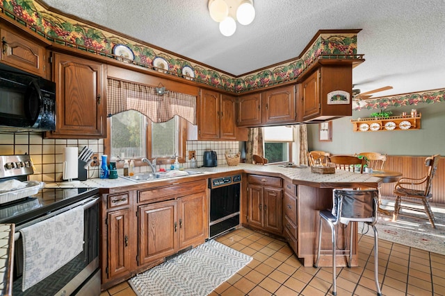 6620 N Straits Hwy, Cheboygan, MI 49721 - kitchen with black appliances, a peninsula, a sink, a textured ceiling, and decorative backsplash