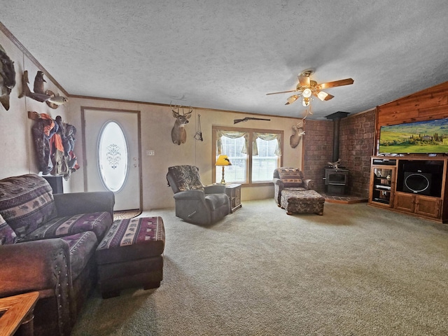 5844 Keipinger Trl, Grayling, MI 49738 - carpeted living room featuring a wood stove, a textured ceiling, a ceiling fan, crown molding, and vaulted ceiling