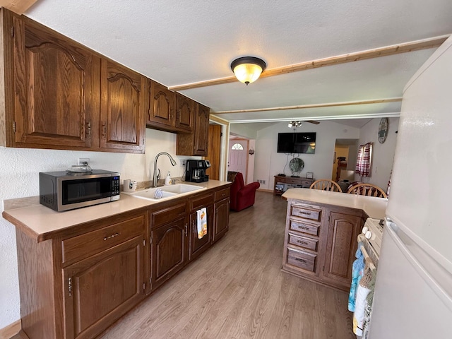10117 M-18, Gladwin, MI 48624 - kitchen with white appliances, light wood-style flooring, light countertops, a sink, and ceiling fan
