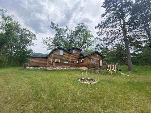 5626 Smith Rd, Lewiston, MI 49756 - back of house with faux log siding, a wooden deck, and a lawn