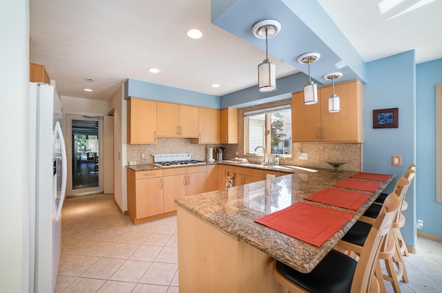 118 Harbor Ct, Houghton Lake, MI 48629 - kitchen featuring light brown cabinetry, a peninsula, decorative backsplash, a breakfast bar area, and stovetop