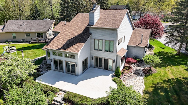 118 Harbor Ct, Houghton Lake, MI 48629 - rear view of house featuring a patio, a lawn, roof with shingles, and a chimney