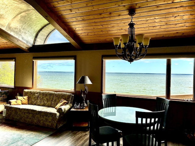 2215 N Partridge Point Rd, Alpena, MI 49707 - dining area featuring a wainscoted wall, a chandelier, a water view, wood finished floors, and wooden ceiling with exposed beams