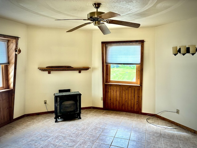2215 N Partridge Point Rd, Alpena, MI 49707 - unfurnished living room featuring a wood stove, baseboards, and ceiling fan