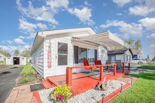 125 Wickham Ave, Houghton Lake, MI 48629 - rear view of property featuring a deck and an outbuilding