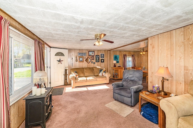 125 Wickham Ave, Houghton Lake, MI 48629 - living area with carpet floors, wooden walls, a ceiling fan, and a wood stove
