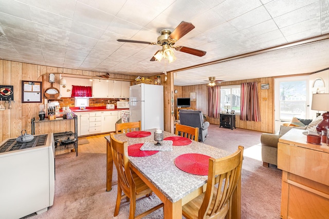 125 Wickham Ave, Houghton Lake, MI 48629 - dining room featuring wooden walls, light colored carpet, and a ceiling fan