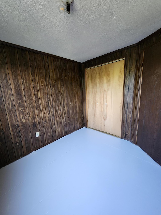 8881 Artesia Beach Rd, Saint Helen, MI 48656 - unfurnished bedroom with wood walls, a closet, and a textured ceiling