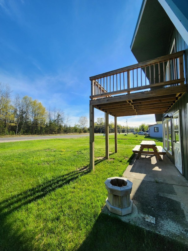 8881 Artesia Beach Rd, Saint Helen, MI 48656 - view of green lawn with a wooden deck, a fire pit, and a patio area