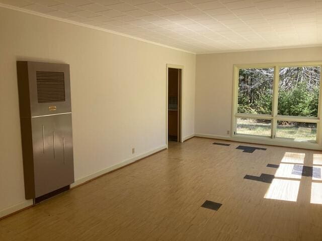 19204 Marlin Ln, Ocqueoc, MI 49759 - unfurnished room with ornamental molding, a heating unit, light wood-type flooring, and baseboards