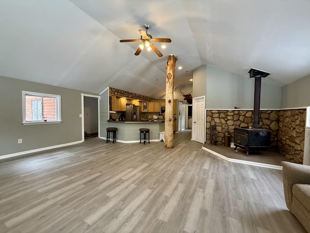 4247 Racoon Trl, Lincoln, MI 48742 - unfurnished living room featuring a wood stove, a ceiling fan, wood finished floors, vaulted ceiling, and baseboards