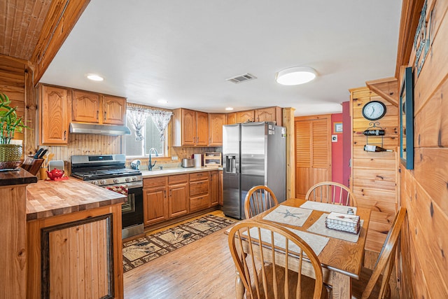 13042 Silver Lake Resort Rd, Wolverine, MI 49799 - kitchen with stainless steel appliances, under cabinet range hood, a sink, wooden counters, and light wood-style flooring