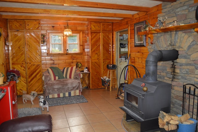 4163 Hanson Rd, Lewiston, MI 49756 - living room with a wood stove, beamed ceiling, tile patterned flooring, and wooden walls