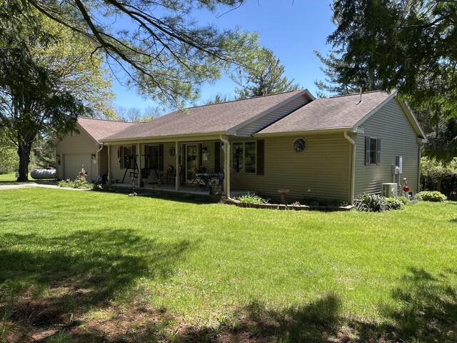 676 N Poor Farm Rd, Harrisville, MI 48740 - back of house with an attached garage, a lawn, roof with shingles, and central AC