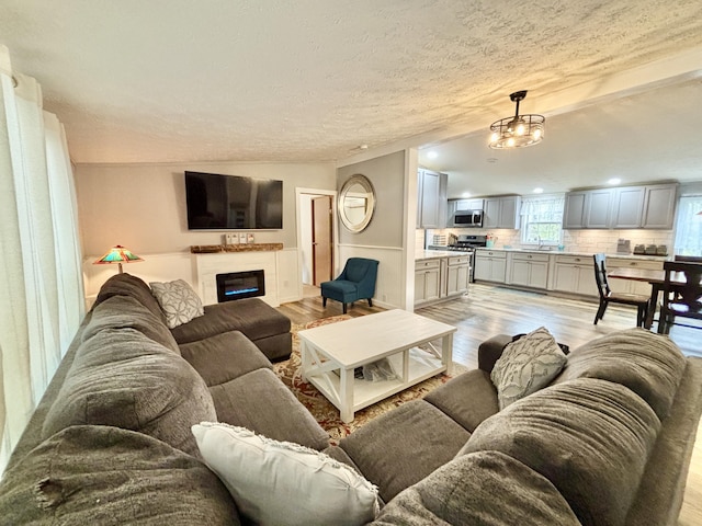 2872 Granger Rd, Lewiston, MI 49756 - living area with light wood-style flooring, a glass covered fireplace, wainscoting, and recessed lighting