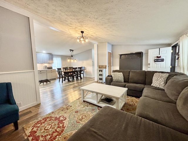 2872 Granger Rd, Lewiston, MI 49756 - living room featuring wood finished floors, a chandelier, a textured ceiling, and wainscoting