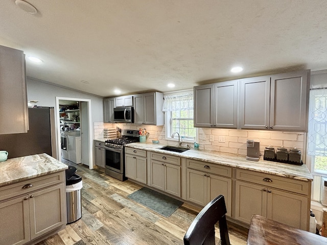 2872 Granger Rd, Lewiston, MI 49756 - kitchen with stainless steel appliances, independent washer and dryer, a sink, light wood-style floors, and backsplash