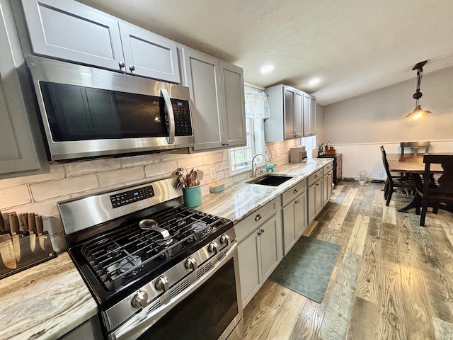 2872 Granger Rd, Lewiston, MI 49756 - kitchen featuring appliances with stainless steel finishes, a sink, light wood-style floors, pendant lighting, and gray cabinetry