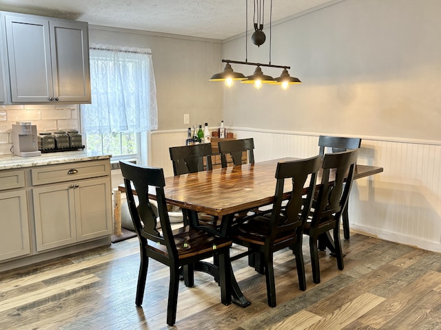 2872 Granger Rd, Lewiston, MI 49756 - dining space with wainscoting, crown molding, light wood-style flooring, and a textured ceiling