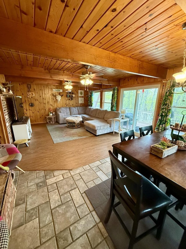 19110 Red Pine Dr, Hillman, MI 49746 - dining space with wood walls, wood ceiling with exposed beams, stone tile flooring, and ceiling fan